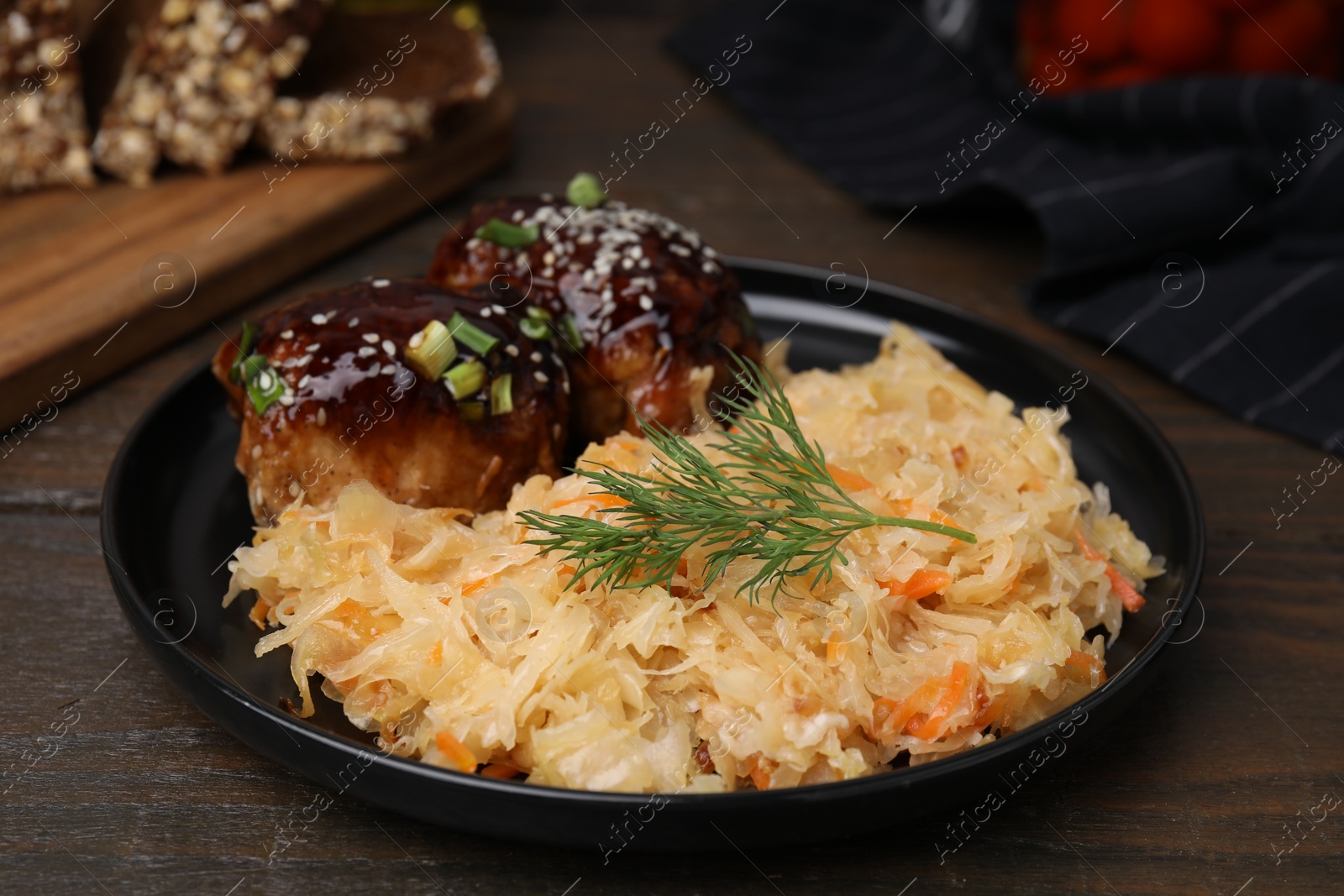 Photo of Plate with sauerkraut and chicken on wooden table, closeup