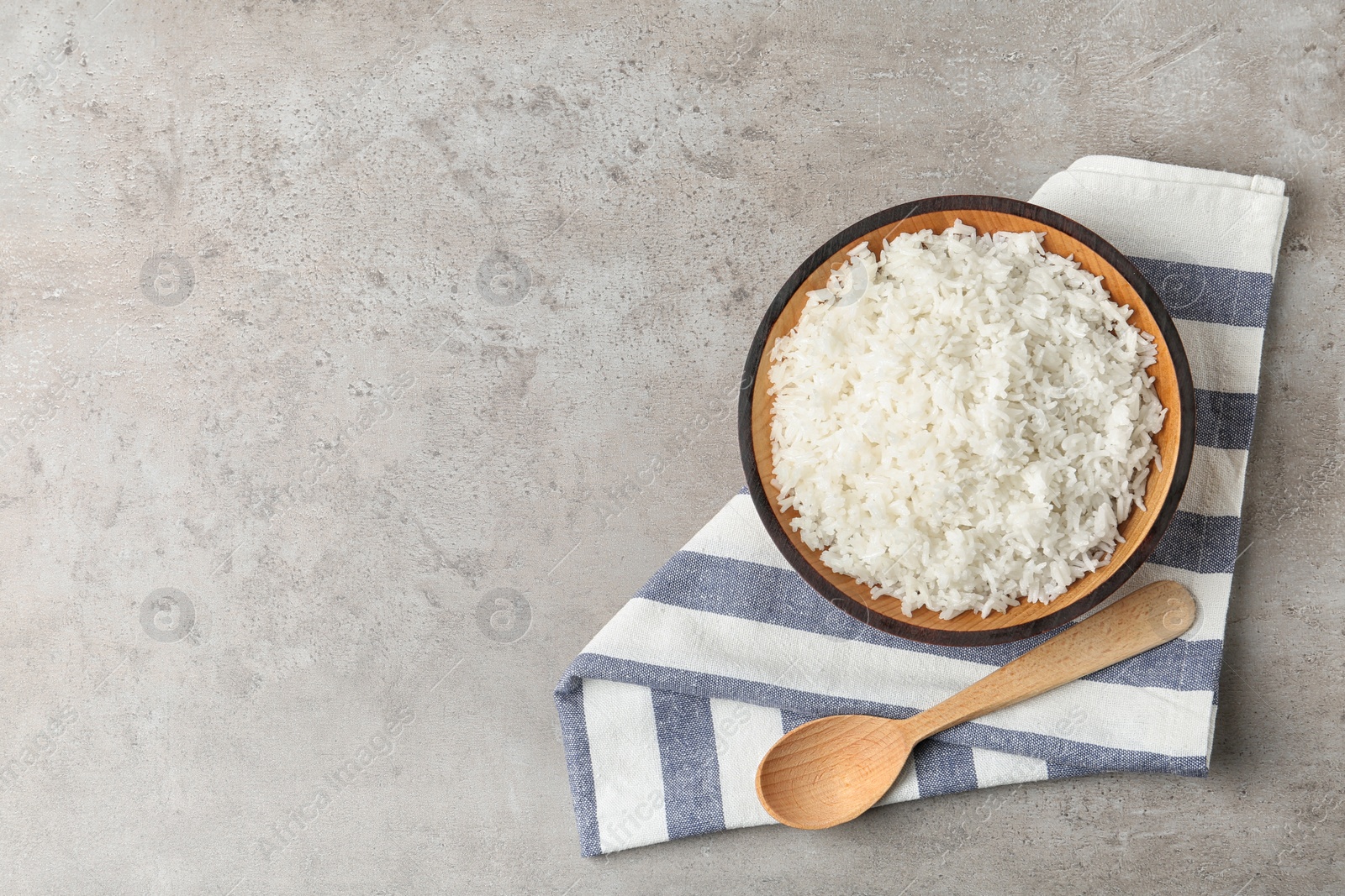 Photo of Bowl of boiled rice and spoon on grey background, top view with space for text