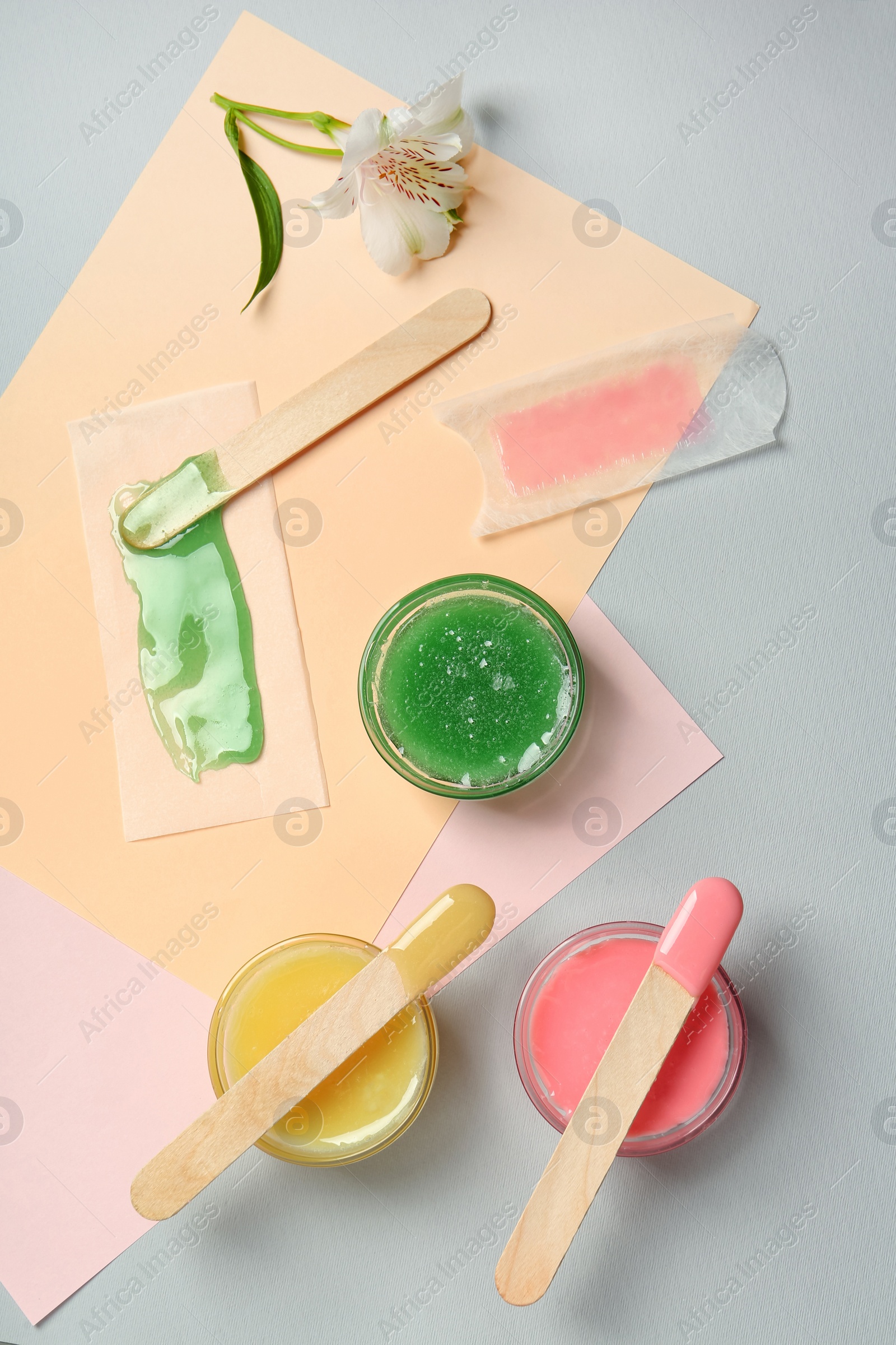 Photo of Flat lay composition with different types of wax and spatulas on color background