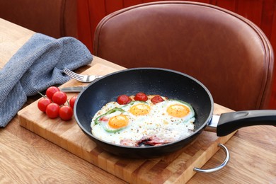 Delicious fried eggs with bacon, tomatoes and pepper served on wooden table