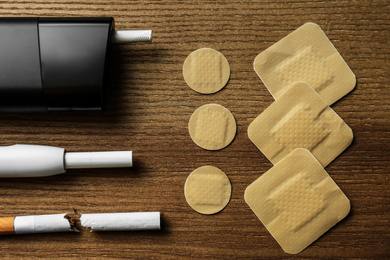 Photo of Flat lay composition with nicotine patches and cigarettes on wooden table