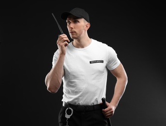 Photo of Male security guard using portable radio transmitter on dark background