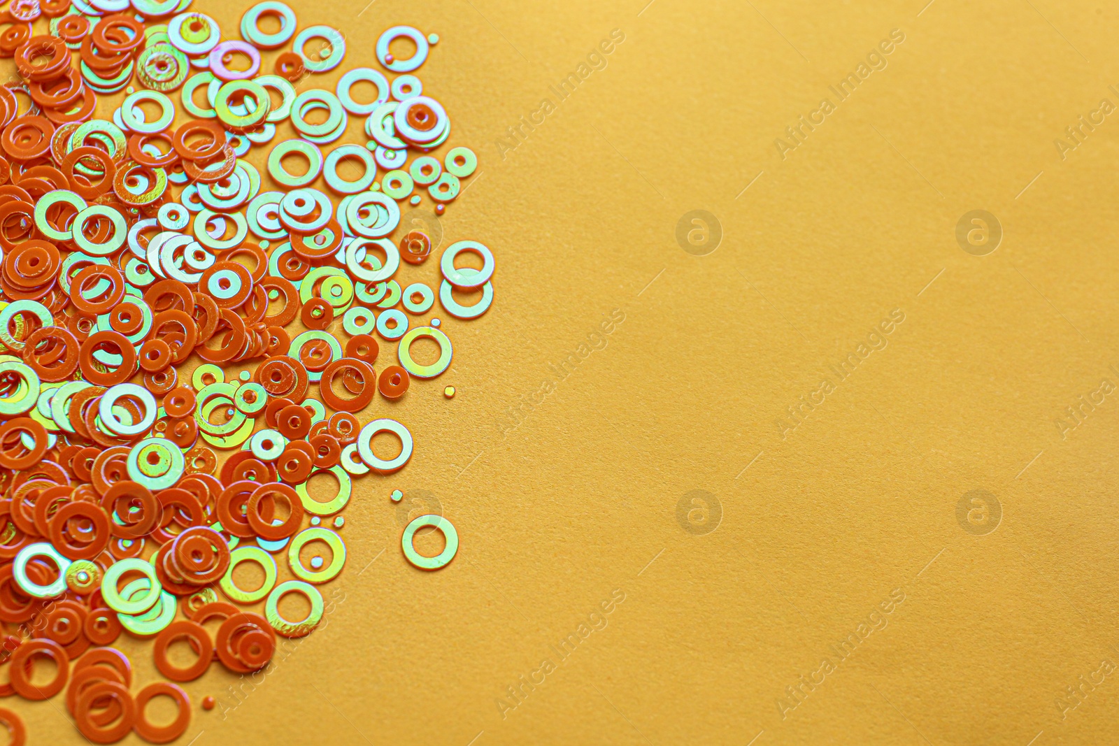 Photo of Shiny bright glitter on pale orange background. Space for text