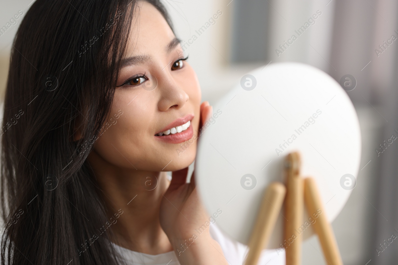 Photo of Woman with perfect skin looking at mirror indoors