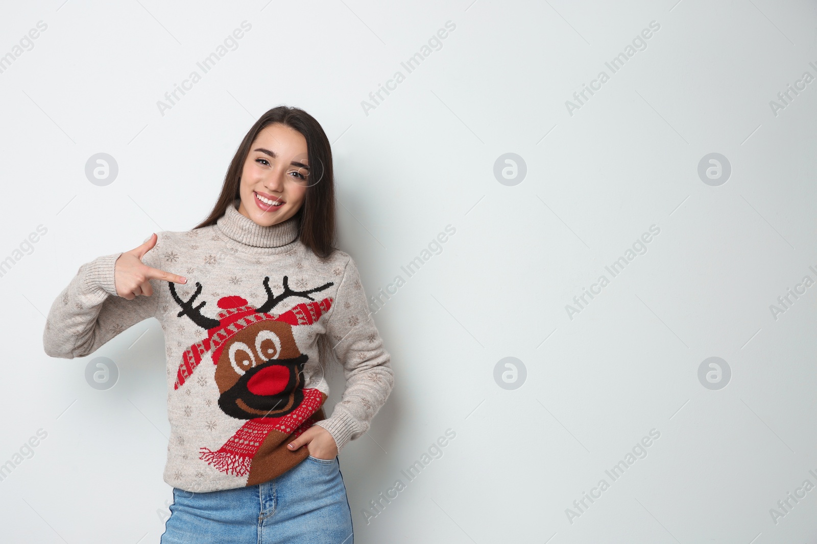 Photo of Young woman in Christmas sweater on white background, space for text