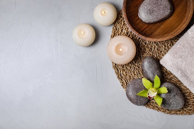 Flat lay composition with spa stones and burning candles on grey table, space for text