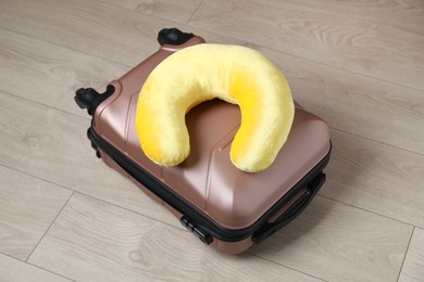 Photo of Yellow travel pillow and suitcase on floor