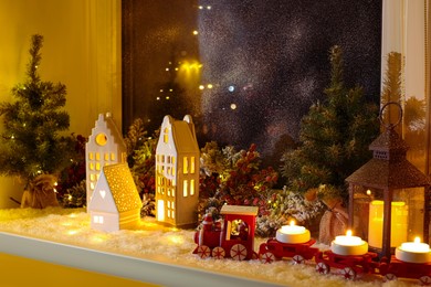 House shaped lanterns and Christmas decor on windowsill indoors