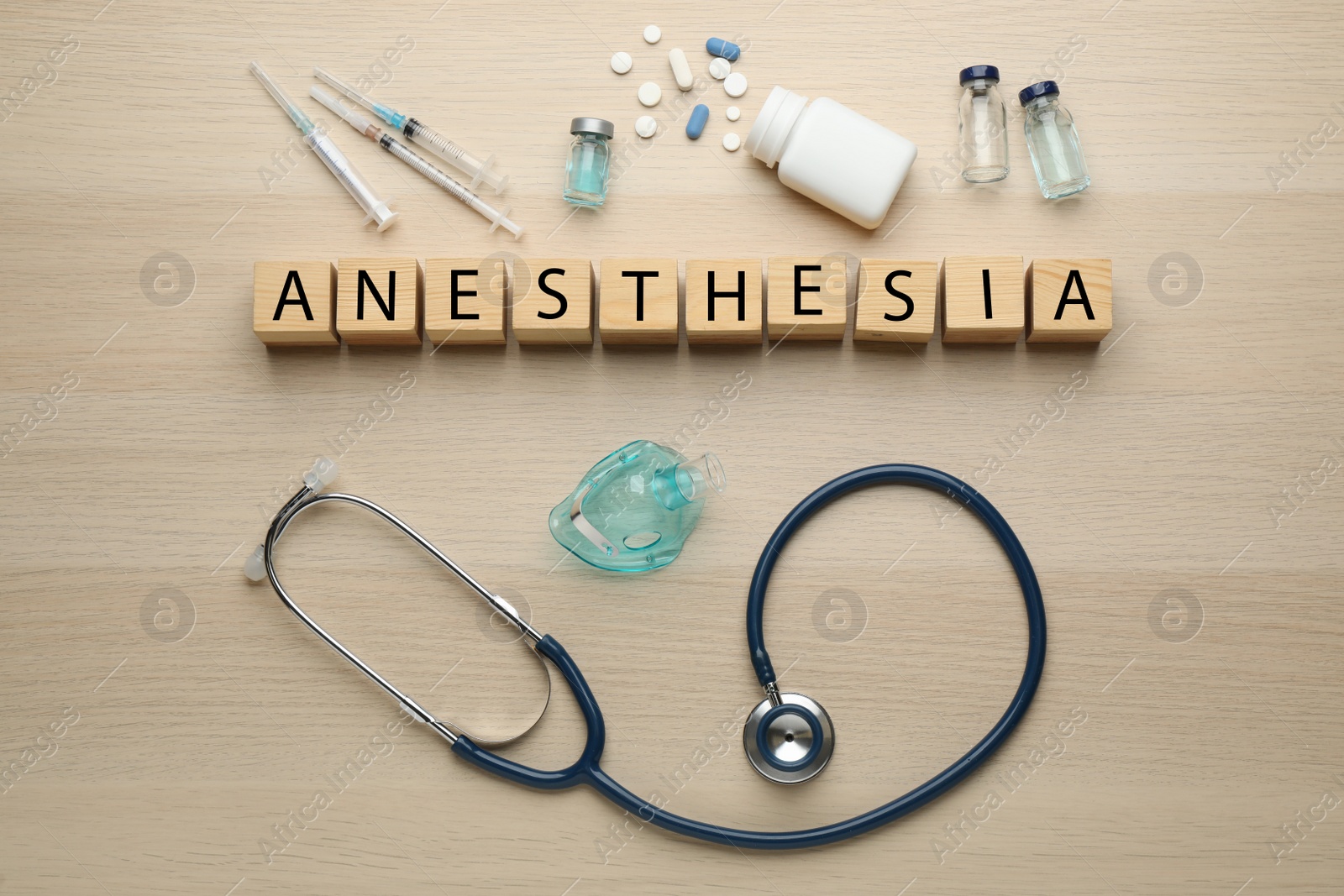 Photo of Word Anesthesia made of wooden cubes, stethoscope and drugs on table, flat lay