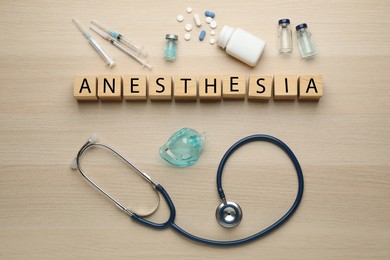 Word Anesthesia made of wooden cubes, stethoscope and drugs on table, flat lay