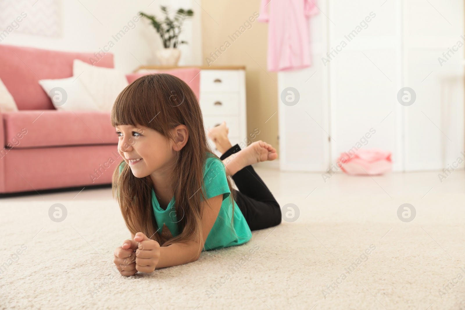 Photo of Cute little girl lying on carpet at home. Space for text