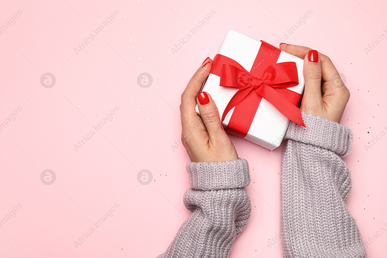 Photo of Young woman holding Christmas gift on pink background, top view. Space for text