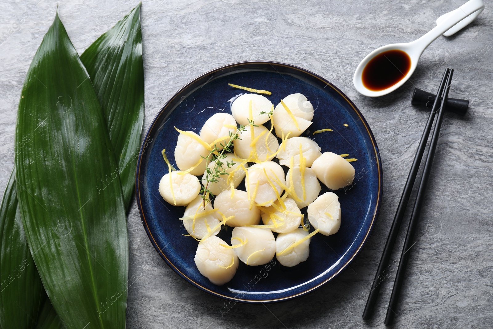 Photo of Raw scallops with thyme and lemon zest served on grey marble table, flat lay