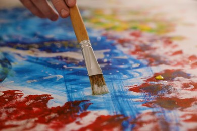 Photo of Man painting on canvas with brush, closeup. Young artist
