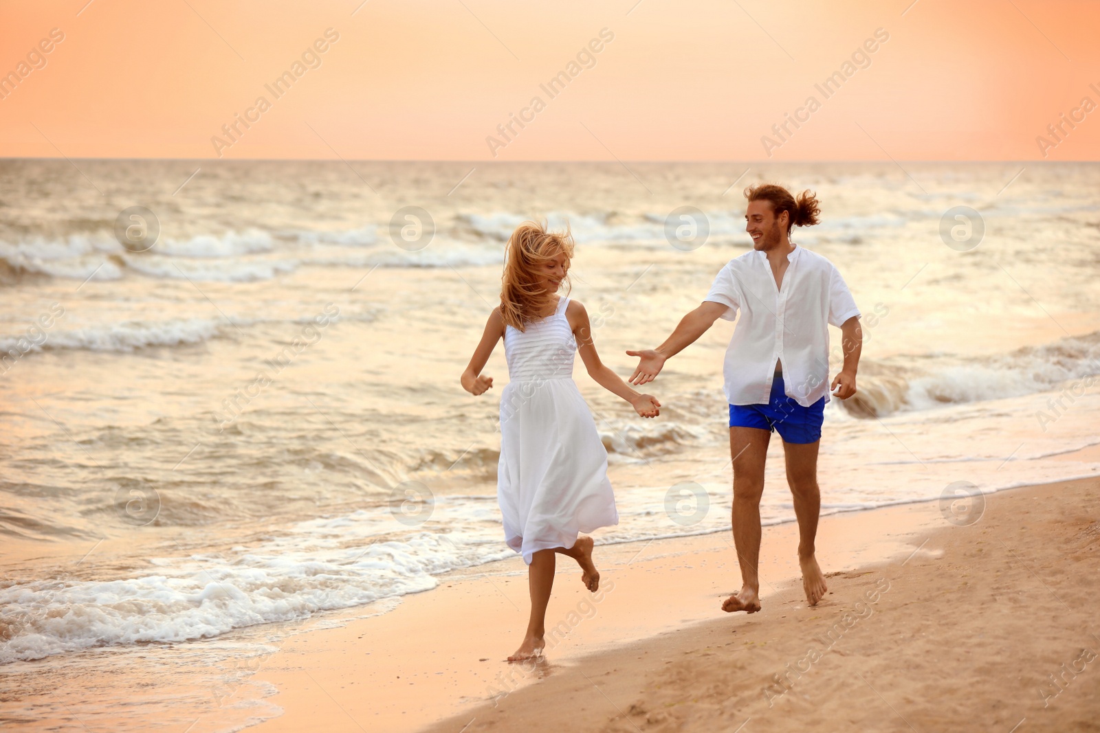 Photo of Young couple having fun on beach at sunset