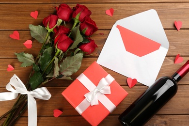 Flat lay composition with beautiful red roses and gift box on wooden background. Valentine's Day celebration