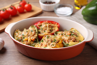 Photo of Tasty stuffed bell peppers in baking dish on wooden table