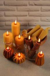 Photo of Beautiful burning beeswax candles on light textured table