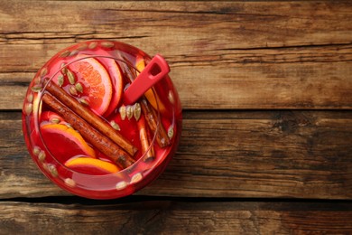 Photo of Glass bowl of aromatic punch drink on wooden table, top view. Space for text