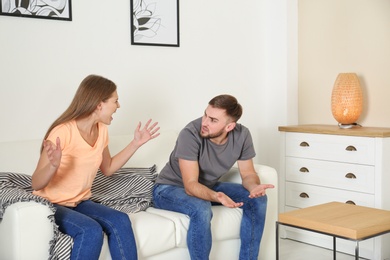Photo of Young couple having argument in living room. Relationship problems