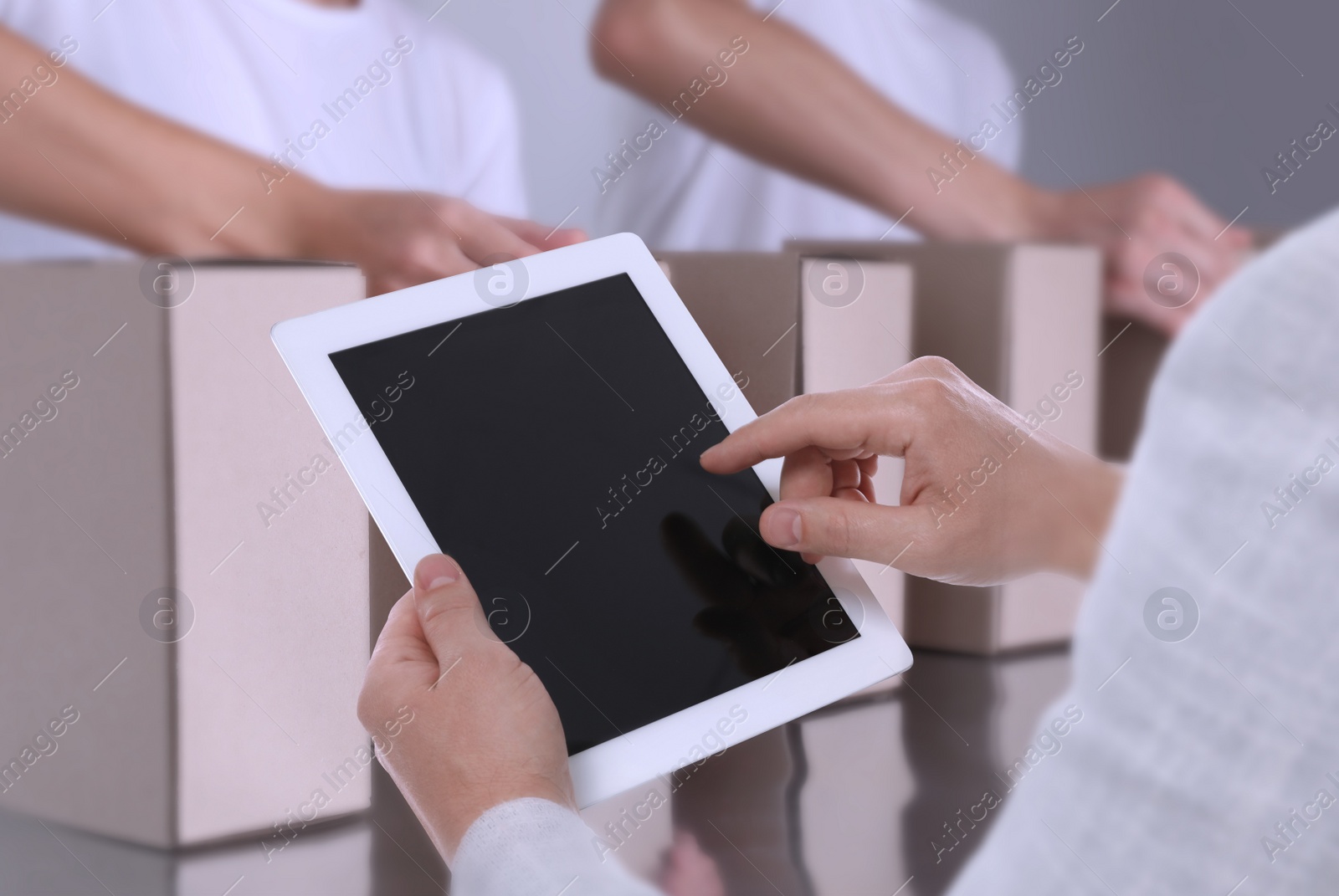 Image of Production line. Manager using tablet while workers folding cardboard boxes, closeup