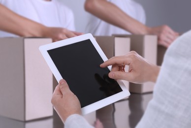 Production line. Manager using tablet while workers folding cardboard boxes, closeup