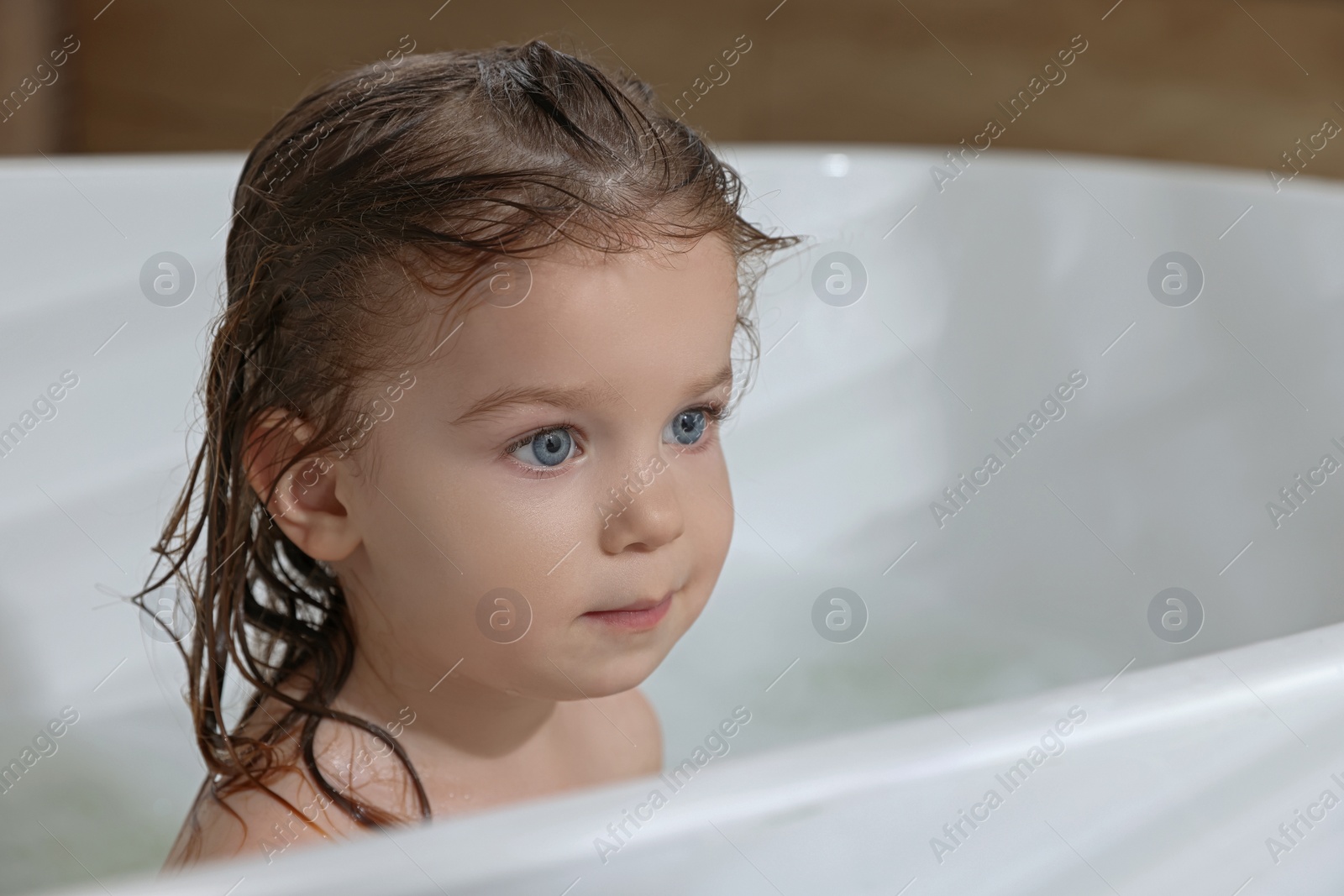 Photo of Cute little girl washing hair with shampoo in bathroom. Space for text