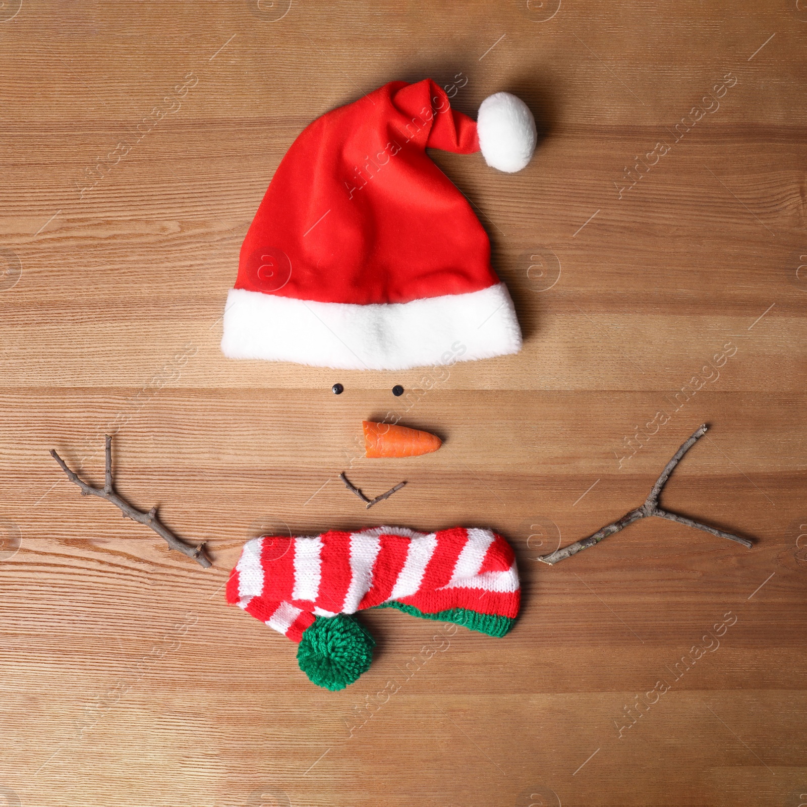 Photo of Funny snowman made with different elements on wooden background, flat lay