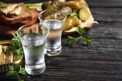 Photo of Cold Russian vodka with snacks on black wooden table, closeup