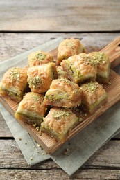 Photo of Delicious fresh baklava with chopped nuts on wooden table. Eastern sweets