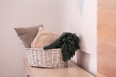 Basket with blankets and pillow on commode indoors