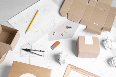 Photo of Creating packaging design. Drawings, boxes and stationery on light wooden table, above view