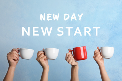 Inspirational text New Day New Start over people holding cups on light blue background