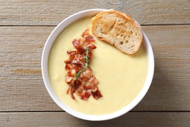 Photo of Tasty potato soup with bacon and crouton in bowl on wooden table, top view