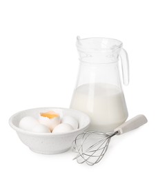 Photo of Whisk, raw eggs and jug of milk isolated on white