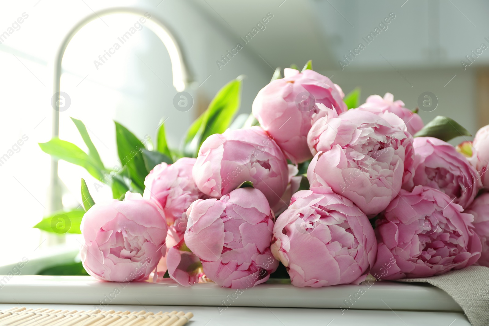 Photo of Bouquet of beautiful pink peonies in kitchen sink