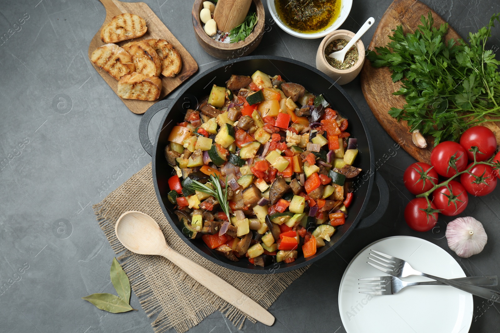 Photo of Delicious ratatouille and ingredients on grey table, flat lay