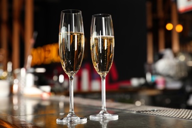 Photo of Glasses of champagne on counter in bar. Space for text