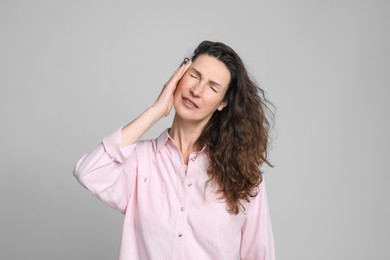 Photo of Mature woman suffering from headache on light grey background