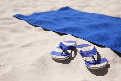 Photo of Flip flops and blue beach towel on sand