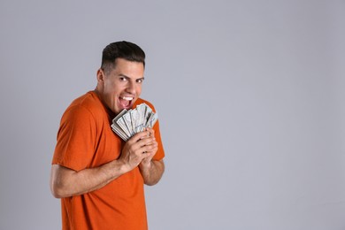 Photo of Greedy man hiding money on grey background, space for text