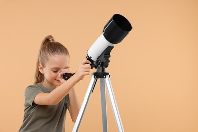 Little girl looking at stars through telescope on beige background, space for text