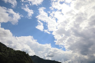 Picturesque view of forest on mountains under beautiful blue sky with fluffy clouds