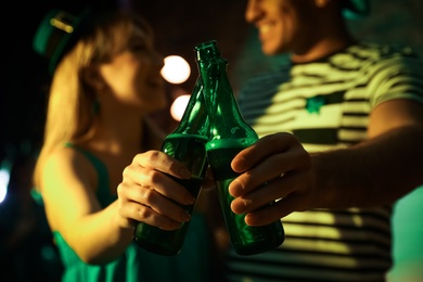 Photo of Couple with beer celebrating St Patrick's day in pub, focus on hands