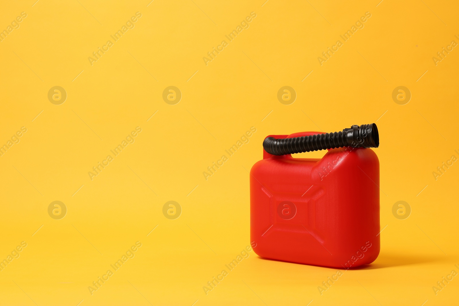 Photo of Red plastic canister with tube on orange background. Space for text