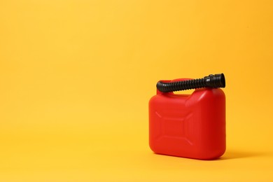 Red plastic canister with tube on orange background. Space for text