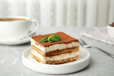 Photo of Delicious tiramisu cake with cup on table