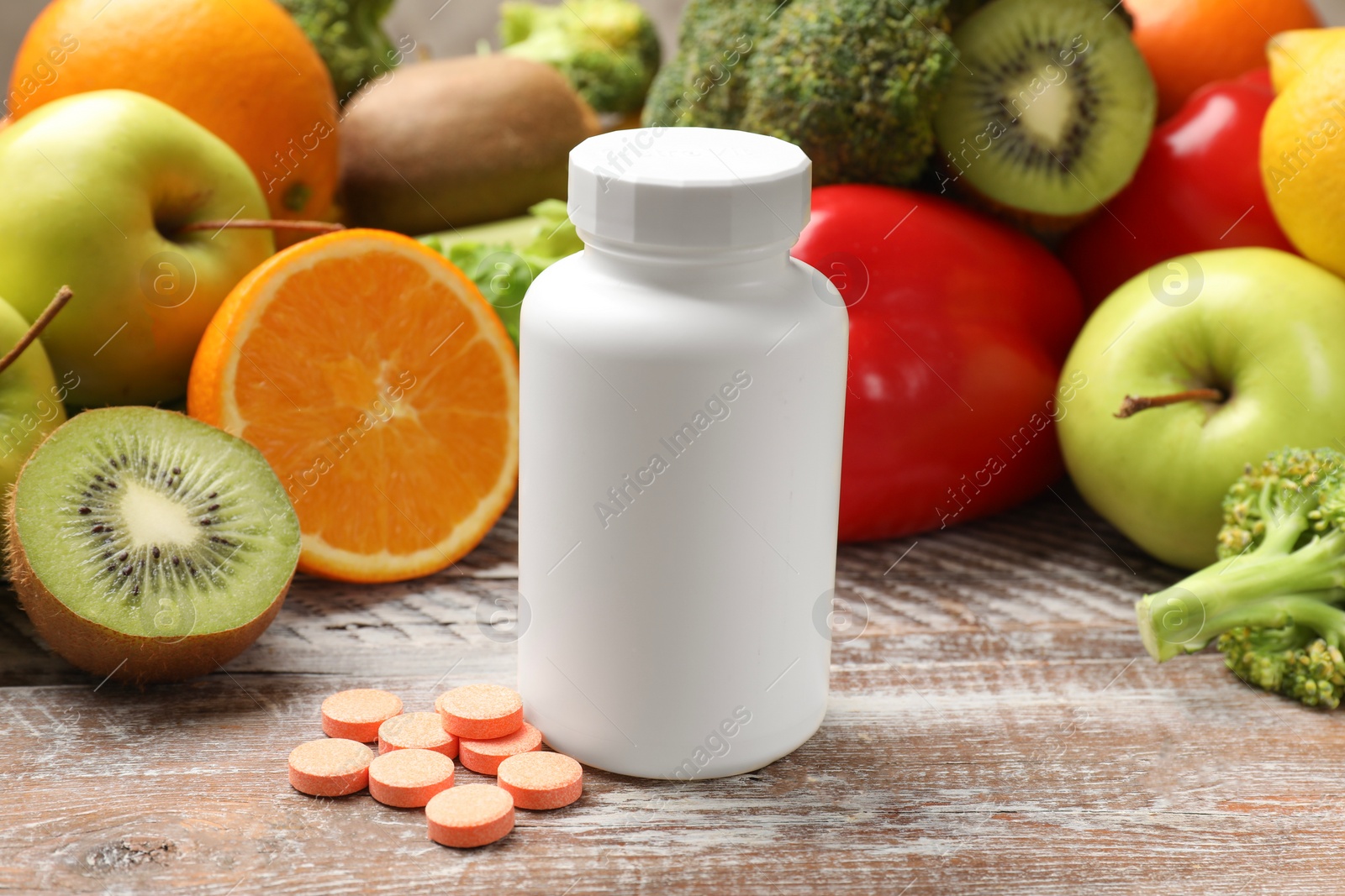 Photo of Dietary supplements. Plastic bottle, pills and food products on wooden table