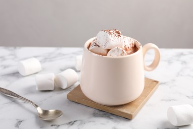 Photo of Cup of aromatic hot chocolate with marshmallows and cocoa powder served on white marble table