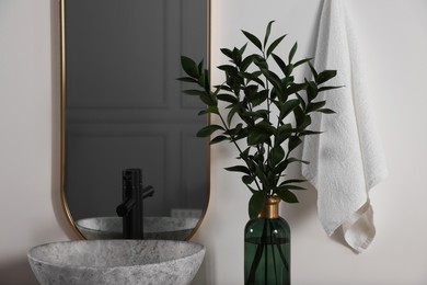 Photo of Stylish mirror over vessel sink and eucalyptus branches in bathroom. Interior design